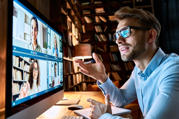 Jonge zakenman die met verschillende collega's praat in een virtuele videoconferentie groepschat met behulp van een computer op het kantoor thuis online professionele videoconferentiecommunicatie sociaal afstandswerkconcept