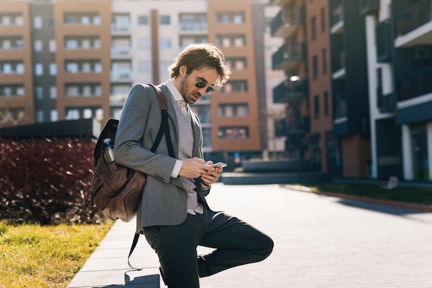 Jonge zakenman die mobiele telefoon gebruikt en een bericht typt in de stad