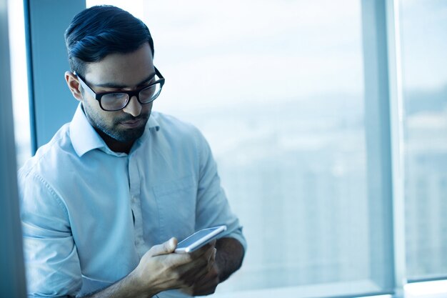 Jonge zakenman die mobiele telefoon met behulp van