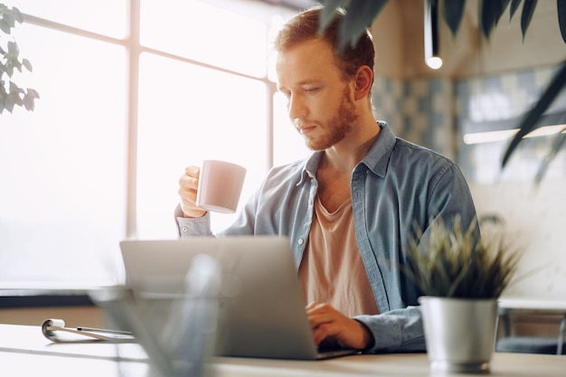 Jonge zakenman die op de computer op kantoor werkt