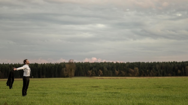 Jonge zakenman die zich in groene weide bevindt en ontspant