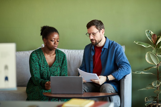 Jonge zakenman en zijn afro-amerikaanse collega in slimme vrijetijdskleding kijken en bespreken alleen