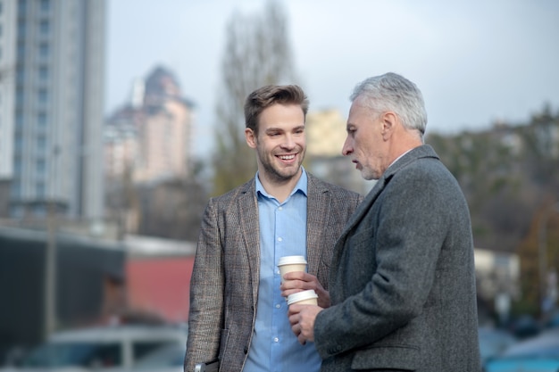 Jonge zakenman en zijn volwassen mentor met een gesprek in de buurt van het kantoor