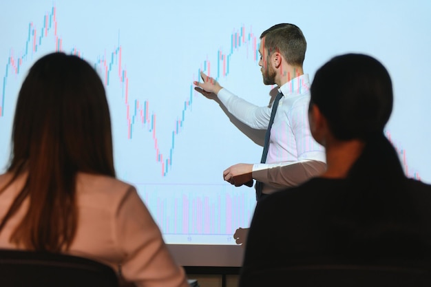 Jonge Zakenman Grafieken Uitleggen Aan Zijn Collega's Op Projector