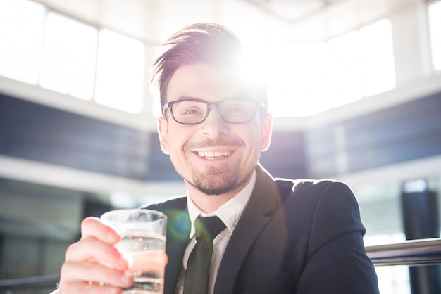 Jonge zakenman houdt een glas water.