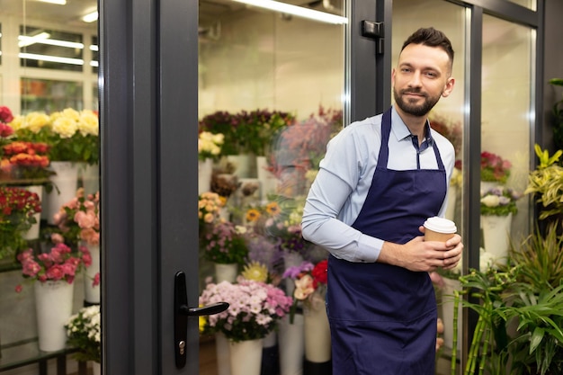 jonge zakenman in een winkel naast een koelkast met bloemen.