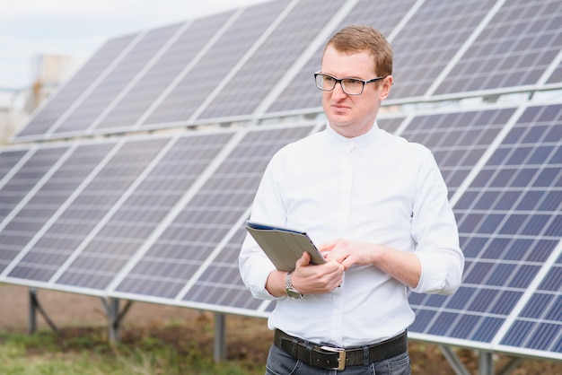 Jonge zakenman in een wit overhemd in de buurt van de zonnepanelen voor elektriciteitscentrales