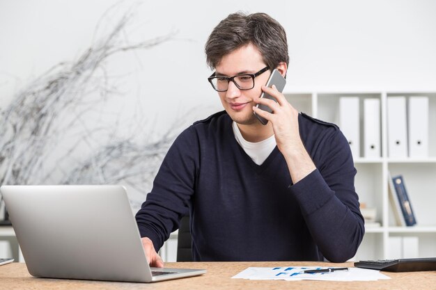 Jonge zakenman in glazen die aan computer werken