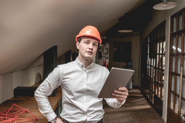 Jonge zakenman in het werk van de bouwvakkerhelm in bouwbedrijf