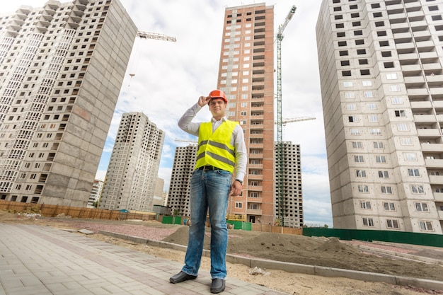 Jonge zakenman in veiligheidshelm en veiligheidsvest die zich op bouwterrein bevinden