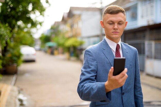 Jonge zakenman met behulp van mobiele telefoon in de straten buitenshuis