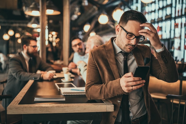 Jonge zakenman met behulp van telefoon in de pub