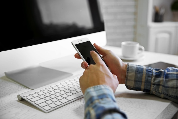 Jonge zakenman met behulp van zijn telefoon en computer close-up