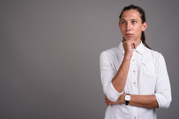 Jonge zakenman met dreadlocks tegen een grijze achtergrond