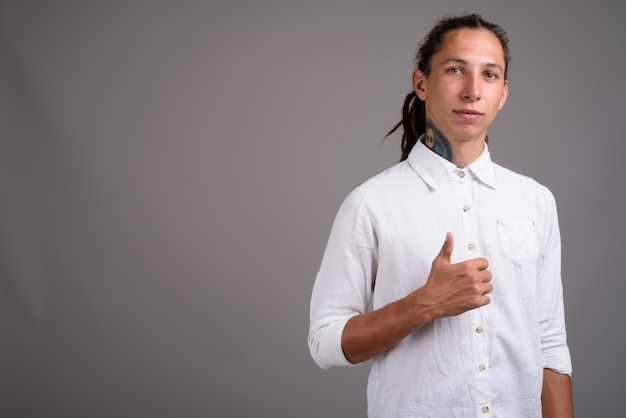 Jonge zakenman met dreadlocks tegen een grijze achtergrond