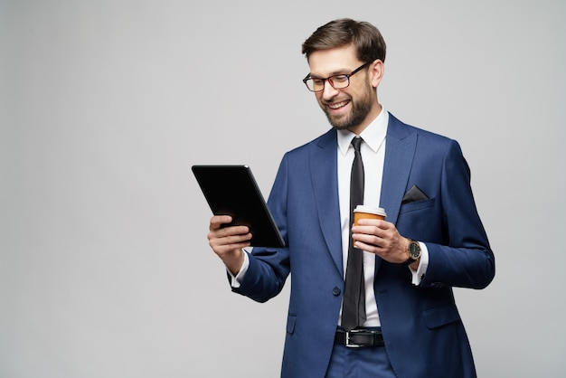 Jonge zakenman met een digitale tablet, pc en een papieren kop koffie