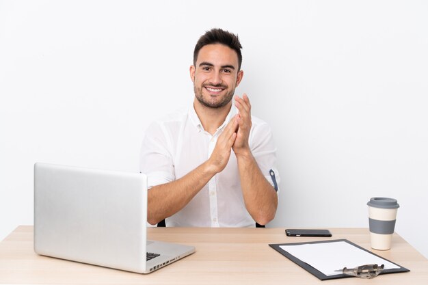 Jonge zakenman met een mobiele telefoon in een werkplaats applaudisseren