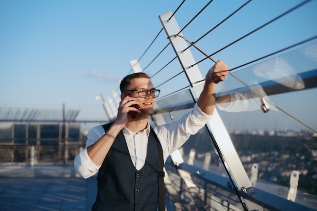 Jonge zakenman met een smartphone die op het terras van een zakencentrum staat. detailopname.