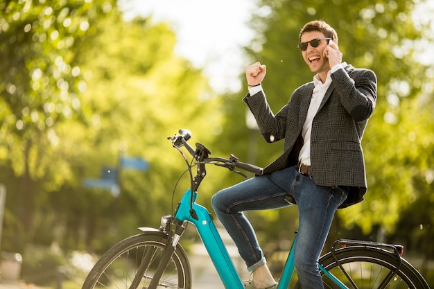 Jonge zakenman op de ebike met behulp van mobiele telefoon