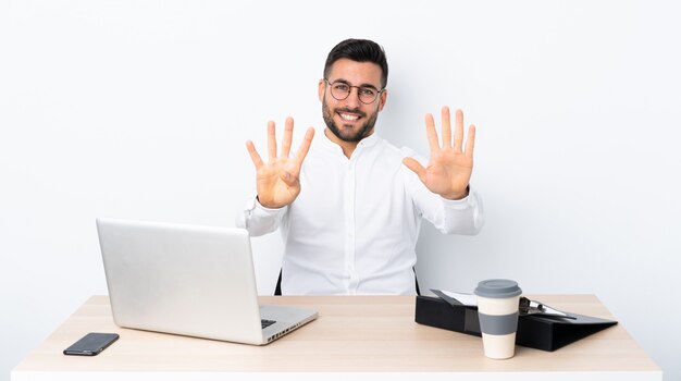 Jonge zakenman op een werkplek die negen met vingers telt