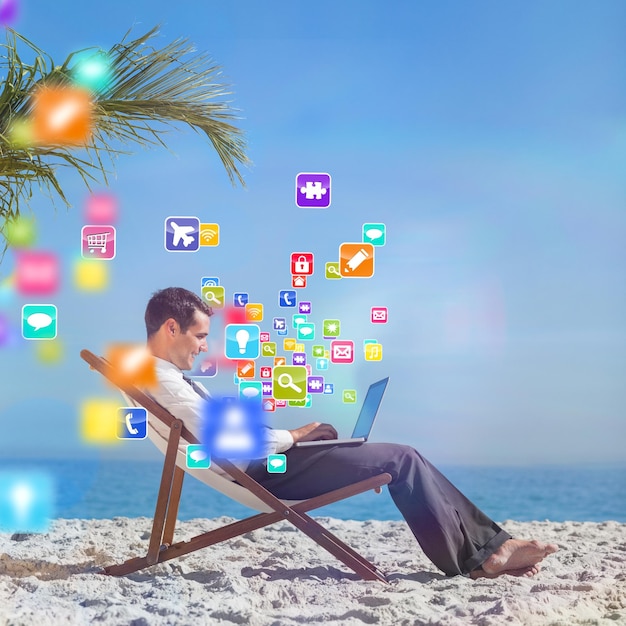 Jonge zakenman op zijn strandstoel met behulp van zijn laptop met kleurrijke computertoepassingen