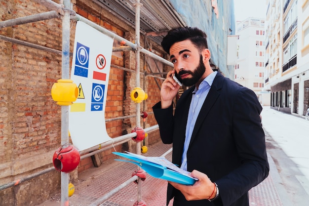 Jonge zakenman poseren met telefoon en map