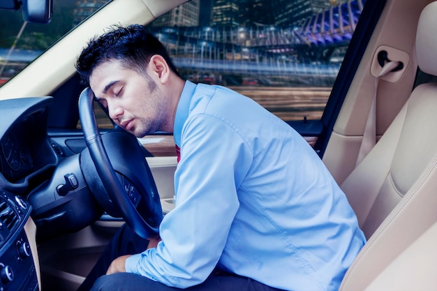 Jonge zakenman slaapt in zijn auto