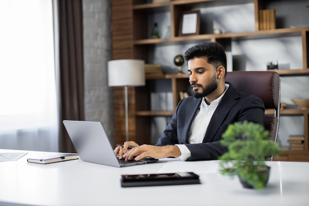 Jonge zakenman typen op laptop tijdens werk op kantoor