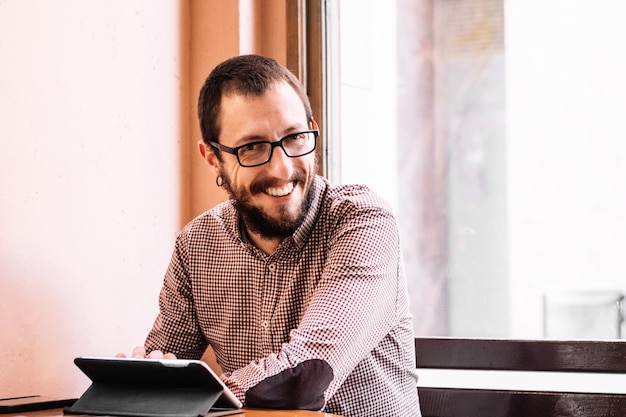 Jonge zakenman werkt op zijn tablet in een café-winkel