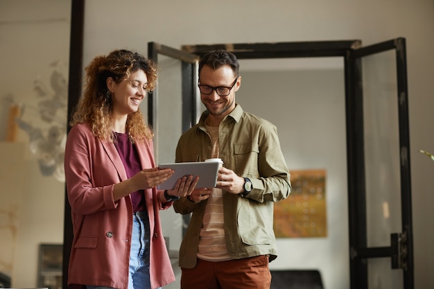 Jonge zakenmensen met behulp van digitale tablet in hun werk en bespreken werken samen terwijl ze op kantoor staan