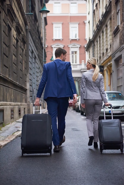 Jonge zakenmensen stellen een stadshotel binnen, zoeken een kamer, houden koffers vast terwijl ze op straat lopen