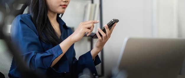 Jonge zakenvrouw aan de telefoon op het kantoor Zakelijke vrouw sms'en op de telefoon en werken op de laptop Mooie jonge zakenvrouw zitten op de werkplek