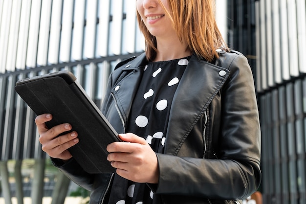 Jonge zakenvrouw die een tablet gebruikt in de buurt van het zakencentrum