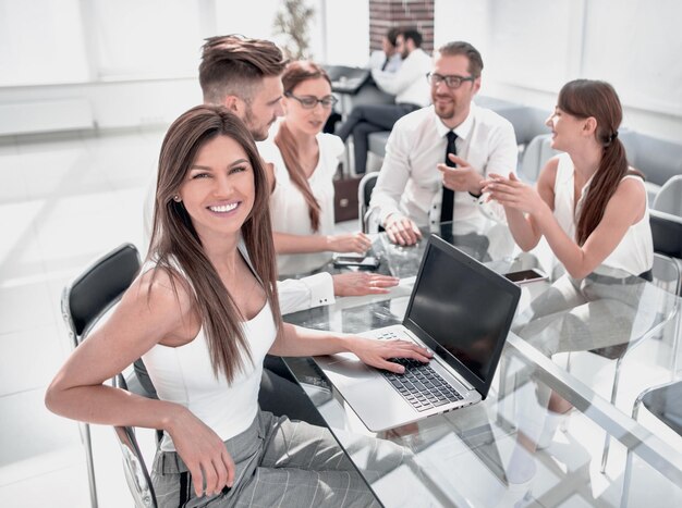 Jonge zakenvrouw en haar collega's zitten aan de kantoortafel