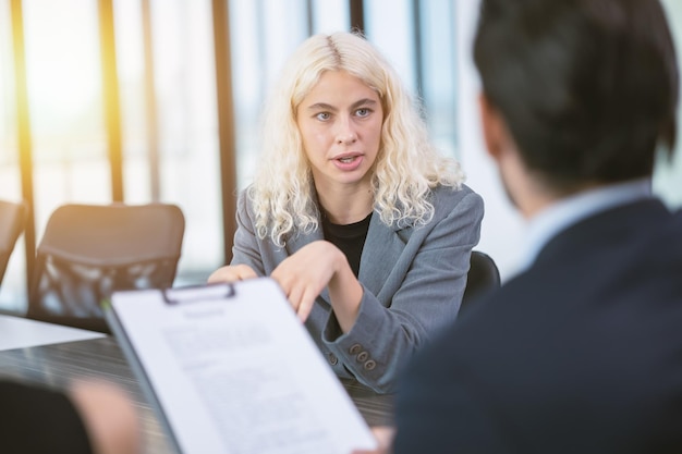 Jonge zakenvrouw gefocuste ogen zelfverzekerd praat aandachtig met je baas in de kantoorvergaderruimte voor een sollicitatiegesprek