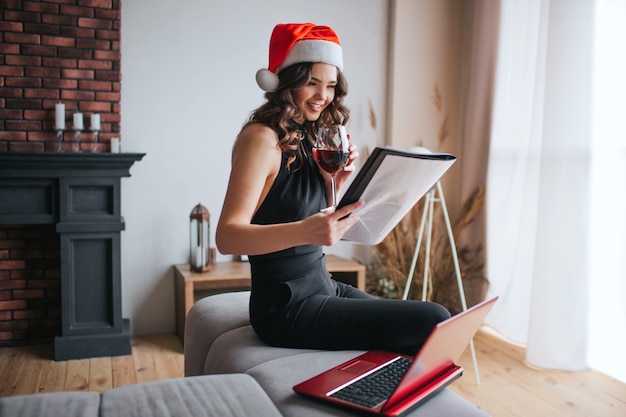 Jonge zakenvrouw in rode kerstmuts thuis werken
