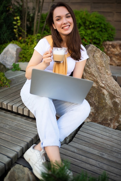 Jonge zakenvrouw koffie drinken en freelance werken op straat.