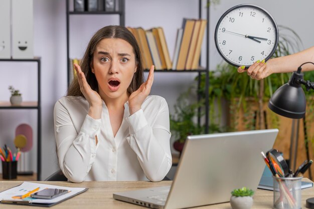 Jonge zakenvrouw met angst die de tijd op de klok controleert, te laat komt op het werk, te laat is met de deadline.