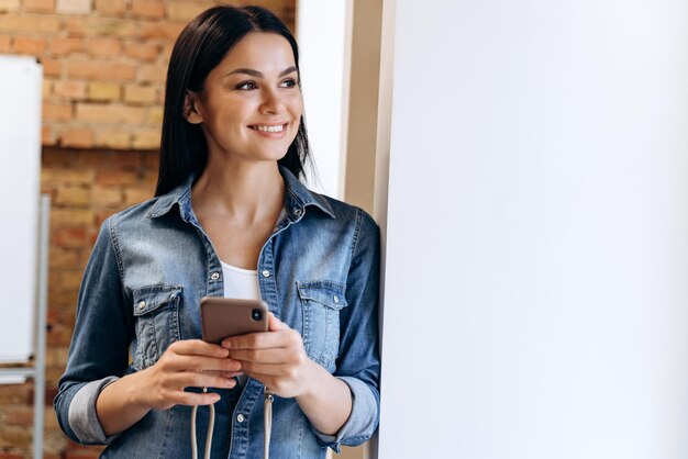 Jonge zakenvrouw met behulp van mobiele telefoon in haar kantoor