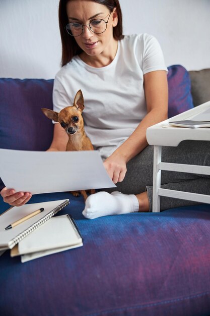 Jonge zakenvrouw met hond die thuis met documenten werkt