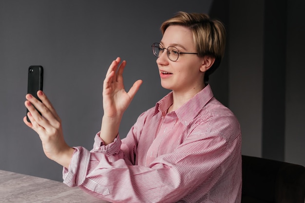 Foto jonge zakenvrouw met kort haar met videogesprek binnenshuis meisje praten aan de telefoon in kantoor blogger-vrouw