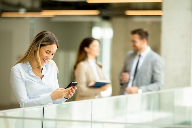 Jonge zakenvrouw met mobiele telefoon in de kantoorgang