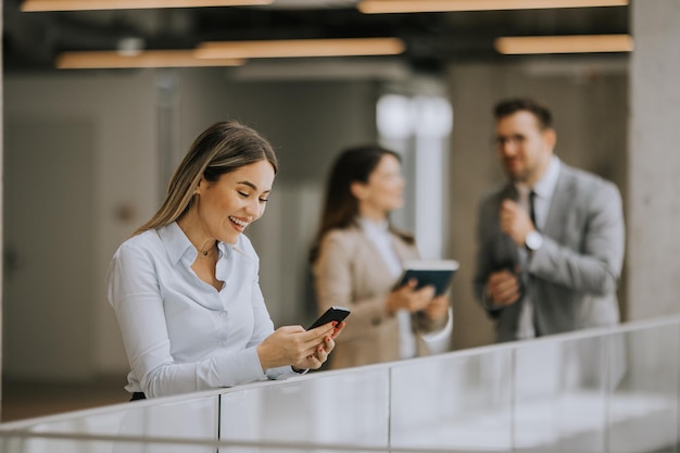 Jonge zakenvrouw met mobiele telefoon in de kantoorgang