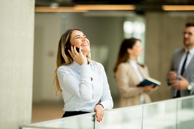 Jonge zakenvrouw met mobiele telefoon in de kantoorgang