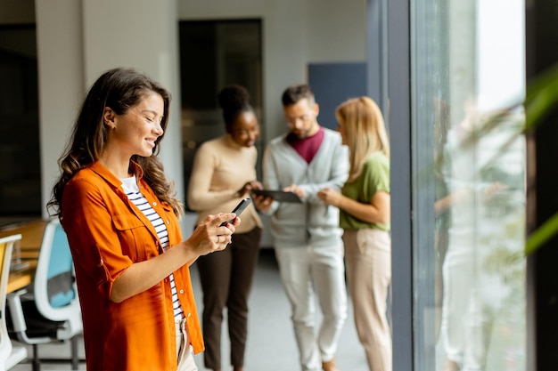 Jonge zakenvrouw met mobiele telefoon voor haar team op het moderne kantoor