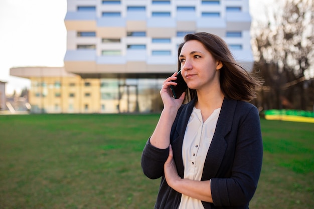 Jonge zakenvrouw praten aan de telefoon op straat in de buurt van het kantoorcentrum