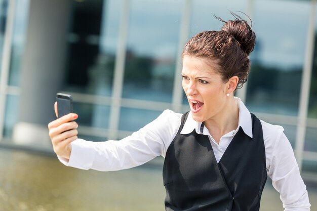 Jonge zakenvrouw schreeuwen op mobiele telefoon