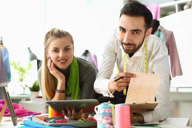 Jonge zakenvrouw stylist naaister bedrijf tablet mannelijke collega toont schetsen van kleding