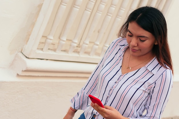 Jonge zakenvrouw typen op mobiele telefoon tijdens het wandelen op een stadspad