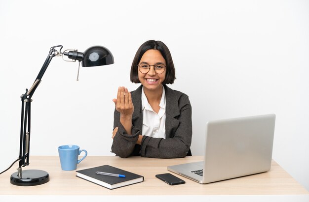 Jonge zakenvrouw van gemengd ras die op kantoor werkt en uitnodigend is om met de hand te komen. blij dat je gekomen bent